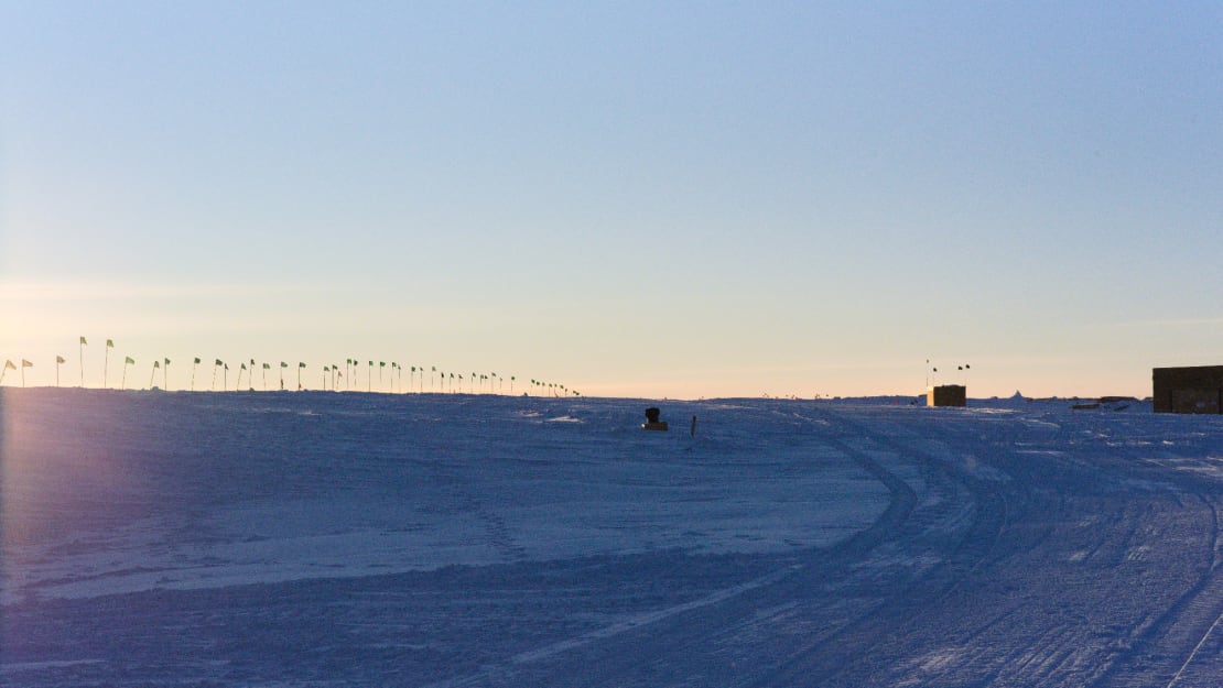 Line of flags seen against a still clear sky before sunset at the Pole.