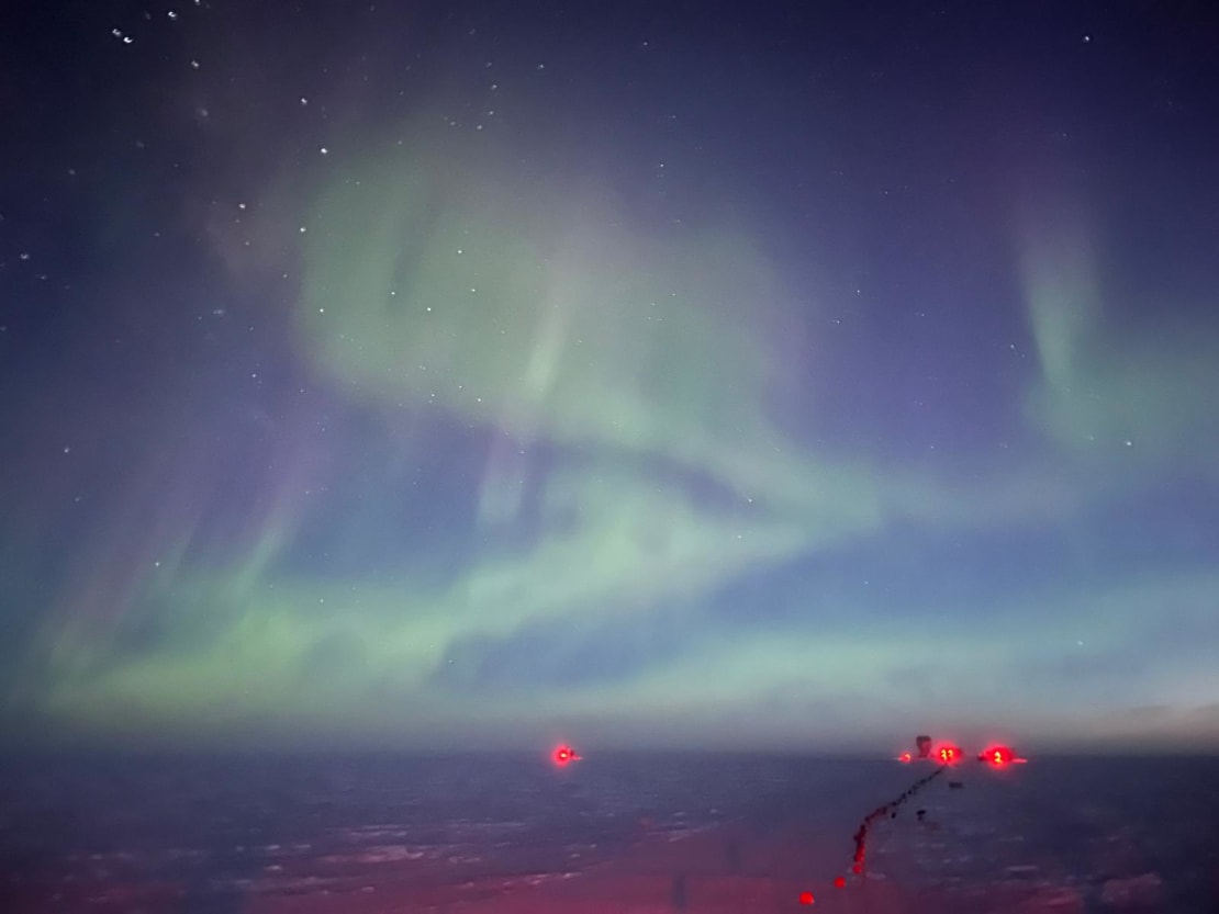 Green swirling auroras at South Pole at twilight.