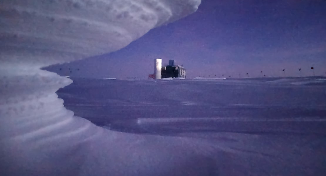 Sastrugi formation left foreground, IceCube Lab centered in distance.