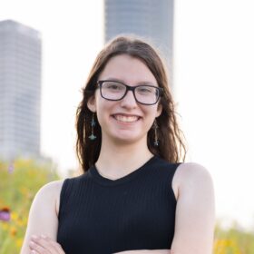 A woman with a black tank top and glasses smiling.