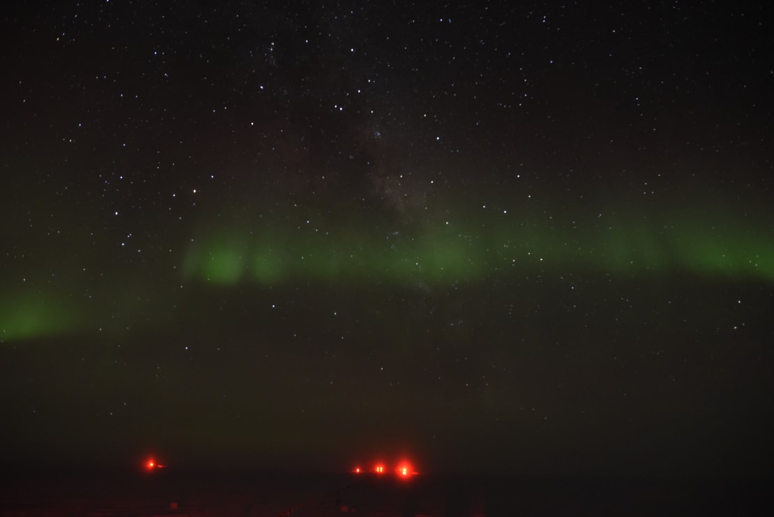 Faint green auroras across dark, starry sky.