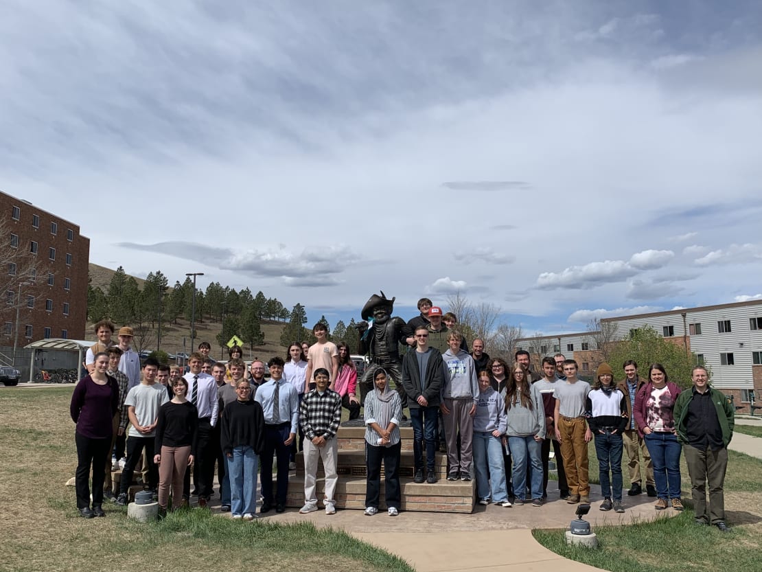 A group of people posing in front of a statue at the South Dakota School of Mines & Technology campus.