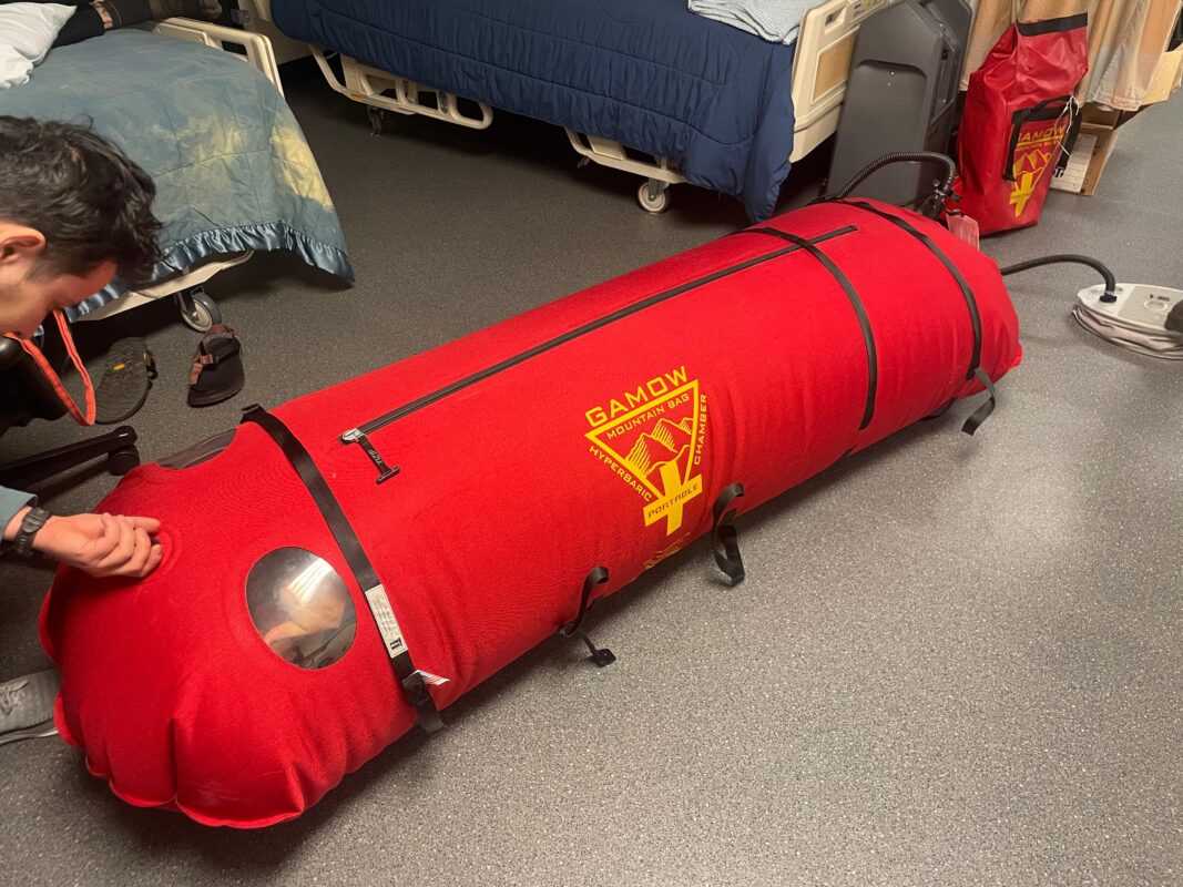 Long red medical-training bag, inflated on the floor.
