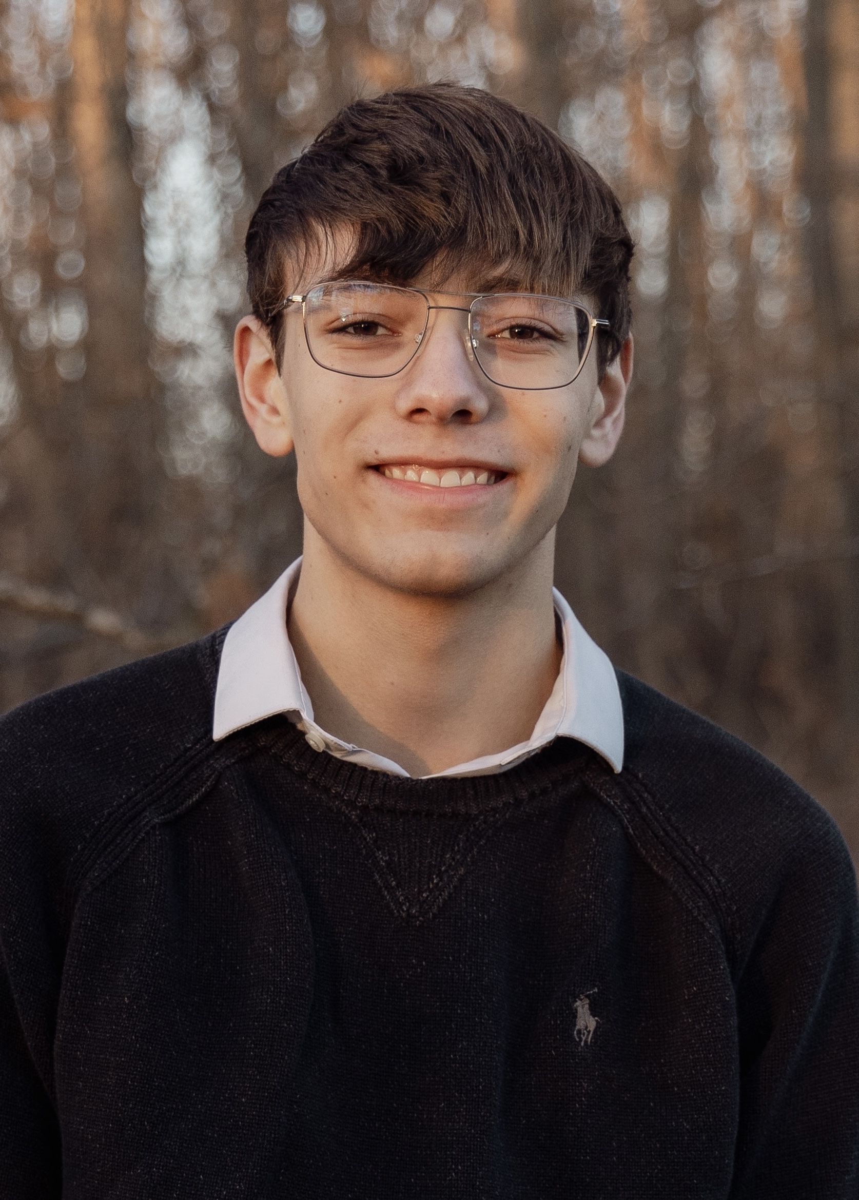 A headshot of a man with glasses and a sweater vest.