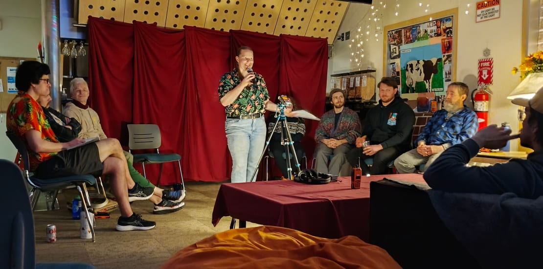 Small group seated around an individual standing before a microphone.