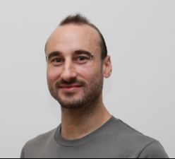 A headshot of a man in a grey shirt.