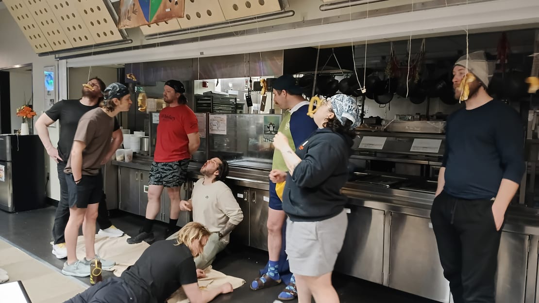 People in a line eating pretzels hanging from strings.