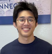 A headshot of a man with short black hair and glasses.
