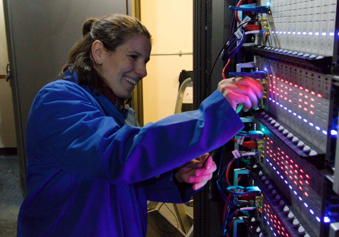 Close-up of someone working at rack of computers.