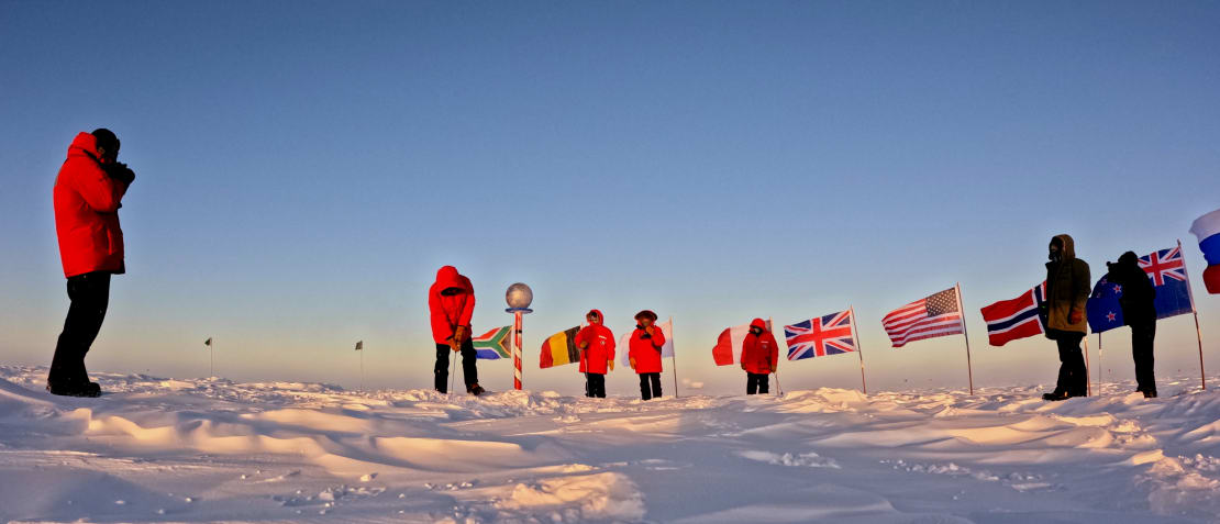 A group in parkas playing golf at the ceremonial South Pole.
