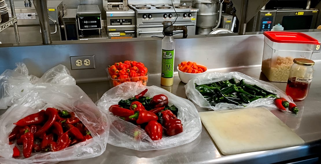 Close-up of three open bags of different types of fresh chili peppers.