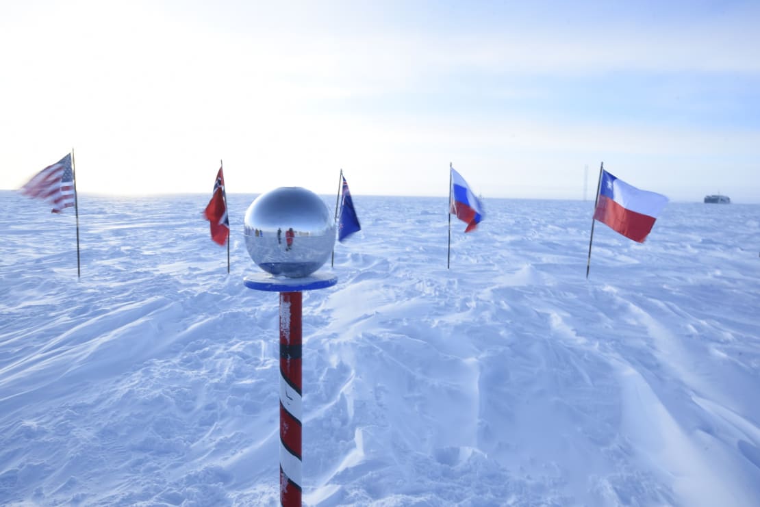 The ceremonial Pole marker at sunrise, with the photographer reflected in the mirrored sphere.